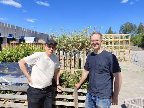 Two men with a forklift pallet of plants awaiting planting in the background.  