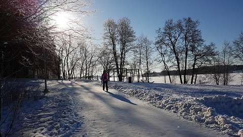 Kuvassa näkyy luminen merimaisema rantaraitilta ja kävelija kävelemässä.