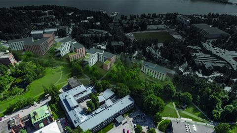 Bostadsbyggnaderna med tegelfasad placeras mellan parken och gatan. I förgrunden syns Aalto-universitetets byggnader, i bakgrunden Teknologbyn och Otnäs idrottspark.