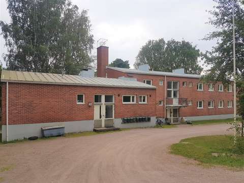 Kuvassa punatiilinen pienkerrostalo, joka on entinen Nöykkiön koulun opettaja-asuntola.