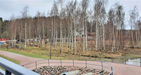 In the foreground are bridge structures and a pedestrian and cycling lane, in the middle some birch trees and in the background a road construction site and detached houses.