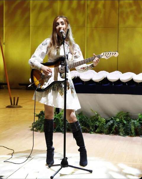 Nuorin nainen laulaa ja soittaa kitaraa ylioppilasjuhlassa.