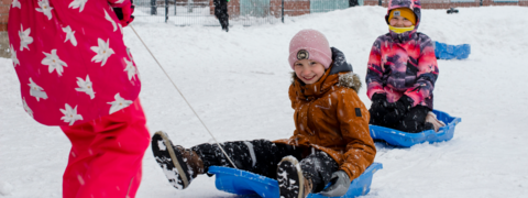 A pupil pulls another pupil on a sledge.