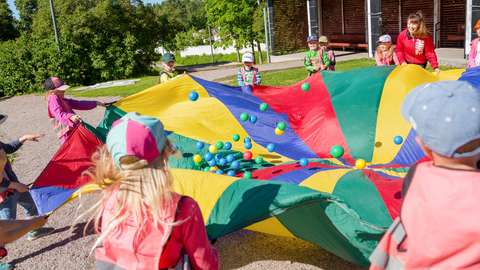 Small children playing with a play parachute.